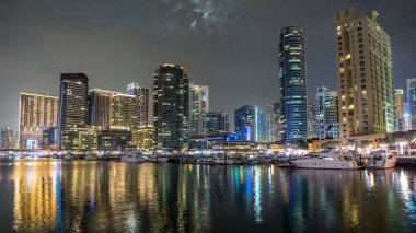Dubai Marina Kuleleri 'nin yüzen yatları ve botları var. Zaman atlaması, Birleşik Arap Emirlikleri. Dubai 'de yapay kanalı olan bir bölge. Bulutlu gökyüzünde dolunay
