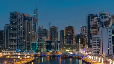 Dubai Marina rıhtımı, Dubai 'deki köprüden gece gündüz geçiş zamanı, Birleşik Arap Emirlikleri. Suni kanalı olan ve güneş doğmadan önce aydınlatılmış gökdelenleri olan bölge.