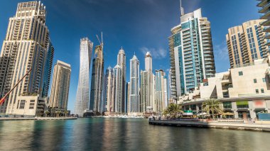 Dubai Marina modern yüksek kuleleri, Birleşik Arap Emirlikleri 'ndeki gezinti zamanı aşırı hızından dolayı suya yansıdı. Dubai 'de bir bölge ve yapay bir kanal. Mavi bulutlu gökyüzü