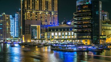 Dubai Marina rıhtımı, yatları ve Dubai 'deki köprüden modern kuleleri olan gece zaman çizelgesi, Birleşik Arap Emirlikleri. Kafeler ve restoranlar