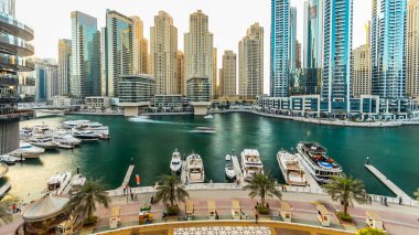 Modern binaları ve geleneksel tekne saatleri olan Dubai marinası. Günbatımı saatinde yukarıdan modern kulelerin en üst hava manzarası