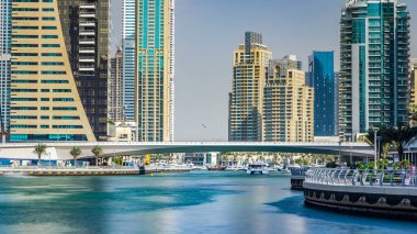 Dubai Marina modern kuleleri ve yüzen yatları ve gezinti güvertesinden botları olan köprü, Birleşik Arap Emirlikleri. Gökdelenlerin en yükseği. Mavi gökyüzü