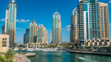 Dubai Marina gezinti güvertesi, palmiyeler, yüzen yatları olan modern kuleler ve köprü zamanından kalma botlar, Birleşik Arap Emirlikleri. Yapay kanal ve gökdelenler