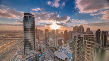 Günbatımında Dubai Marina 'nın tekneleriyle modern gökdelenler ve su kanalları, Birleşik Arap Emirlikleri. Renkli bulutlu gökyüzü ve karayolu trafiği ile hava üstü görüntüsü