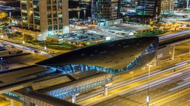 JLT bölgesi yakınlarındaki metro istasyonunda gece trafiği var. Dubai marina gökdelen çatısı havadan görünüyor.