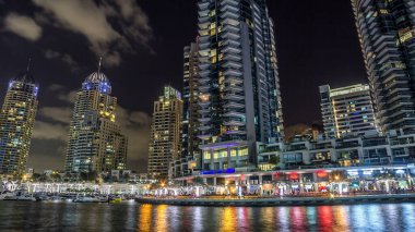 Dubai Marina gezinti güvertesinde yatlar ve modern kuleler ile Dubai 'deki deniz kıyısından yansıyan su, Birleşik Arap Emirlikleri. Dubai Marina, Dubai 'de bir şehirdir..