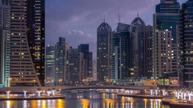 Dubai Marina Kanalı, modern kuleleri ve yatları olan liman kenti Dubai 'deki köprüden gece gündüz geçiş zamanı olan Birleşik Arap Emirlikleri' ne yansıyor. Güneş doğmadan önce etraftaki gökdelenler
