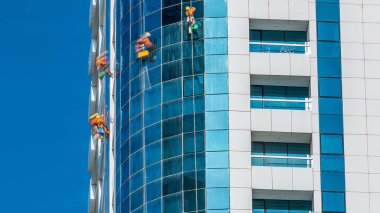 Dubai, BAE 'deki modern gökdelenin camlarını siliyorlar. Güneşli günde manzarayı kapat