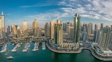 Dubai Marina gezinti güvertesi ve kanalı, Dubai, BAE 'de yüzen yat ve teknelerle gün batımı görüntüsü. Modern kuleler ve yol trafiği panoramik manzara
