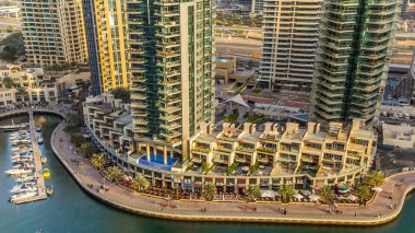 Dubai Marina gezinti güvertesi ve kanalı gündüz vakti Dubai, BAE 'de yüzen yat ve teknelerle hava görüntüsü. Günbatımından önce yollarda modern kuleler ve trafik