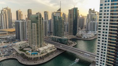 Dubai Marina gezinti güvertesi ve kanalı, gün batımından sonra Dubai, BAE 'de yüzen yat ve tekneler ile gündüz hava manzaralı. Modern kuleler, köprü ve trafik yukarıdan geliyor.