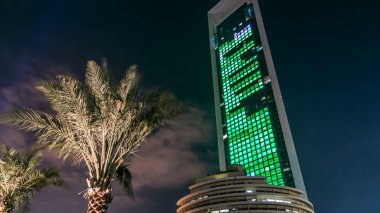 Geceleri iş yerlerindeki modern binaların zaman çizelgelerine bak. Parlak pencereli cam cepheli gökdelenler. Ekonomi ve finans kavramı. Abu Dabi, BAE