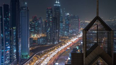 Modern skyscrapers and busy evening highways night timelapse in luxury downtown of Dubai city. Top aerial view from tower rooftop. Dubai, United Arab Emirates