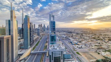 Dubai gökdelenleri, gün batımı akşam vakti. Dubai metro istasyonu ve Şeyh Zayed Yolu 'ndaki trafik. Kule çatısından gökyüzü görüntüsü. Güzel renkli bulutlu gökyüzü