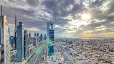 Dubai gökdelenleri, gün batımı akşam vakti. Dubai metro istasyonu ve Şeyh Zayed Yolu 'ndaki trafik. Kule çatısından gökyüzü görüntüsü. Güzel renkli bulutlu gökyüzü ve güneş ışığı