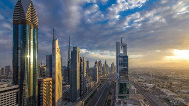 Dubai gökdelenleri akşam saatlerinde güneş camlarında yansıyor. Dubai metro istasyonu ve Şeyh Zayed Yolu 'ndaki trafik. Kule çatısından gökyüzü görüntüsü. Renkli bulutlu gökyüzü ve güneş ışığı