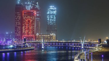 Dubai Su Kanalı, şehrin ufuk çizgisi gece zaman çizelgesi, Birleşik Arap Emirlikleri. Gökdelenler suya yansıyor. Köprüden görüntüle
