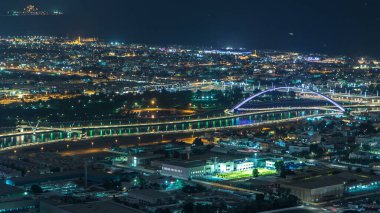 Dubai su kanalı zaman ayarlı ve gece boyunca teknelerin geçtiği ışıklı köprüler var. Kule çatısından gökyüzü görüntüsü. Deniz kıyısındaki ışıklardan gelen suya yansıyan yansıma