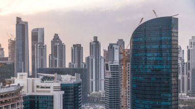 Dubai iş hangarı kuleleri gün batımında hava zaman tünelinde. Bazı gökdelenlerin çatı manzarası ve inşaat halindeki yeni kuleler.
