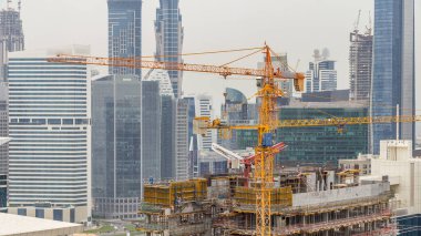 İnşaat alanında Dubai timelapse, Birleşik Arap Emirlikleri. Sarı vinç ve işçi üniformalı. İş defne gökdelenler hava Üstten Görünüm