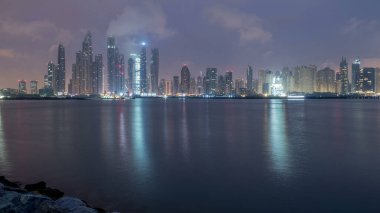 Gün geçiş timelapse Dubai şehir gece Palm Jumeirah Adası'içinde modern gökdelenler Panoraması. Dubai, Birleşik Arap Emirlikleri. Dubai Yat Limanı ve sabah erken bulutlara Jbr