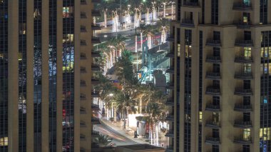 Birds eye view of Dubai skyline timelapse and rush hour traffic in downtown at night. Road with palms between houses clipart