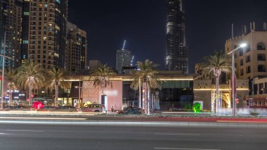 Dubai siluetinin timelapse ve acele saat trafik gece şehir merkezinde cadde görünümü. Avuç içi ve arka plan üzerinde modern kuleleri olan yol
