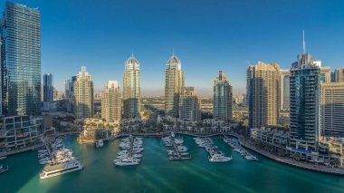 Dubai Marina gökdelenleri, hava zaman çizelgeleri, lüks yatları ve marina gezinti güvertesi olan liman, Dubai, Birleşik Arap Emirlikleri. Gölgeler gün batımında hareket eder