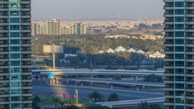 Dubai Marina gökdelenleri hava zaman çizelgesi, Dubai, Birleşik Arap Emirlikleri. Gölgeler gün batımında hareket eder. İki kule arasındaki yolda trafik vardı.