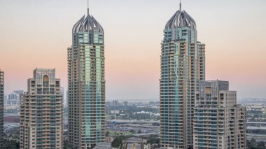 Dubai Marina gökdelenleri hava gününden geceye geçiş zamanı, lüks yatları ve marina gezinti güvertesi olan liman, Dubai, Birleşik Arap Emirlikleri. Aydınlatılmış kuleler ve yol trafiği