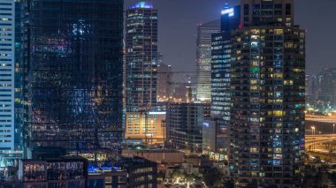 Dubai Yat Limanı gece timelapse, Glittering ışıklar ve en yüksek gökdelenler. Işıklı kuleleri ve arka plan üzerinde yolda trafik