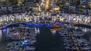 Dubai Marina Fıskiyesi, gece uçuş saati, lüks yatları ve marina gezinti güvertesi olan liman, Dubai, Birleşik Arap Emirlikleri. Aydınlatılmış avuçlar ve yol trafiği