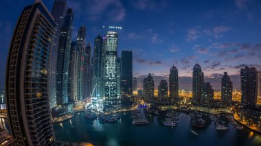 Dubai Marina 'da gündoğumundan önce Dubai, BAE' de yatları olan modern gökdelenlerin gece gündüz geçiş zamanı panoraması. Sabahın erken saatlerinde aydınlık kuleler