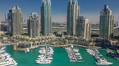 Dubai Marina gökdelenleri, hava zaman çizelgeleri, lüks yatları ve marina gezinti güvertesi olan liman, Dubai, Birleşik Arap Emirlikleri. Mavi gökyüzü ve zümrüt su