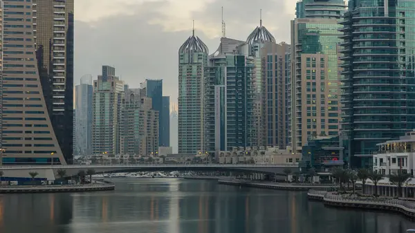 Morning view of Dubai Marina canal, waterfront with modern towers and yachts reflected in water from bridge in Dubai sunrise time timelapse, United Arab Emirates.