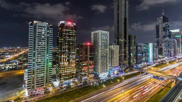 迪拜市中心的塔楼夜间经过 有摩天大楼的谢赫扎耶德公路的空中景观 公路和地铁的交通 闪烁的灯光和小径 — 图库照片