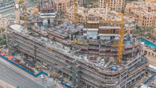 Construction site in Dubai timelapse, United Arab Emirates. Yellow cranes and workers in uniform. Aerial top view