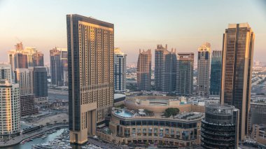 Dubai Marina akşam uçuşunun gün batımı görüntüsü, BAE. Modern gökdelenler ve turuncu ışıklı binalar. Yapay kanal şehrindeki alışveriş merkezinin yakınındaki yatlar ve tekneler.