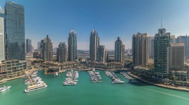 Dubai Marina gökdelenleri gün batımına kadar tüm gün boyunca gökdelenler, lüks yatlar ve marina gezinti güvertesi, Dubai, Birleşik Arap Emirlikleri. Gölge çok hızlı hareket eder. Mavi gökyüzü ve zümrüt su