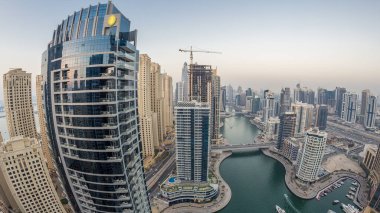 Dubai Marina gezinti güvertesi ve kanalı, gün batımından sonra Dubai, BAE 'de yüzen yat ve teknelerle panoramik hava manzaralı. Modern kuleler ve yoldaki trafik.