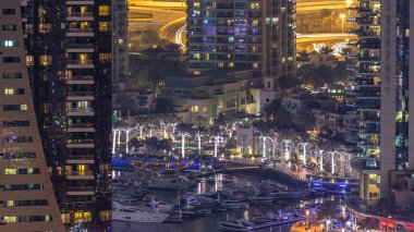 Su kanalı ve Dubai Marina manzarası, gece timelapse güvertede. Konut kuleleri aydınlatma ve aydınlatma ile. Yat ve tekne trafiği olan gökdelenler yüzen