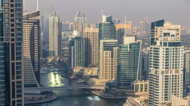Gün batımında inanılmaz renkli Dubai marinası silueti. Yatları ve tekneleri olan çok uzun gökdelenler için harika bir perspektif. Binaların üzerinde güneş ışığı. Birleşik Arap Emirlikleri.