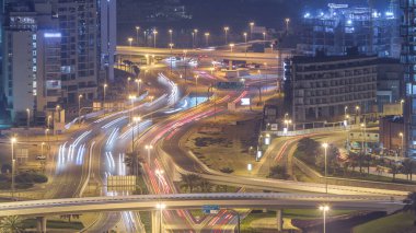 Bir büyük şehir gece timelapse bir yol kavşak hava görünümünü. Arabalar ve gökdelenler ile UAE Dubai Yat Limanı bölgesinin kentsel peyzaj.
