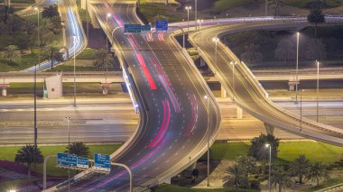 Bir büyük şehir gece timelapse bir yol kavşak hava görünümünü. Arabalar ve metro hattı ile UAE Dubai Yat Limanı bölgesinin kentsel peyzaj.