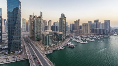 Dubai, BAE 'de gün batımından sonra yüzen yat ve teknelerle Dubai Marina gezinti güvertesi ve kanalı üzerinden geçen güzel bir gökyüzü çizgisi. Modern kuleler ve köprüdeki trafik.