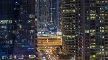Konut kuleleri aydınlatma ve aydınlatma timelapse ile. Yol ve Dubai Yat Limanı ve Jlt manzarası, gece güvertede. Rating gökdelenler ile parlayan pencere eşiği yanında