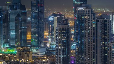 Dubai şehir merkezinde gece saatleri modern aydınlık gökdelenler, alışveriş merkezleri ve yol trafiği. Yukarıdan iş sahasının en üst görüntüsü