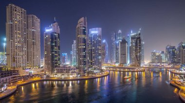 Su kanalı ve Dubai Marina manzarası, gece timelapse güvertede. Konut kuleleri aydınlatma ve aydınlatma ile. Yat ve tekne trafiği olan gökdelenler yüzen