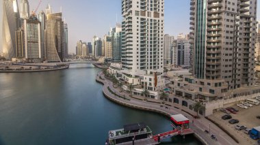 Gün batımında Dubai marinası gökyüzüne yükseliyor. Yatları ve tekneleri olan çok uzun gökdelenler için harika bir perspektif. Binaların üzerinde güneş ışığı. Birleşik Arap Emirlikleri.