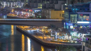 Su kanalı ve Dubai Marina manzarası, gece timelapse güvertede. Konut kuleleri aydınlatma ve aydınlatma ile. Yat ve tekne trafiği olan bir köprü gökdelenler yüzen